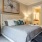 Large, carpeted bedroom with queen bed, and nightstand lamps.