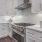 Kitchen with white granite countertops and what tile backsplash and under cabinet lighting.